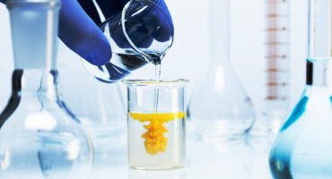 Two clear liquids are mixed to produce a yellow precipitate.